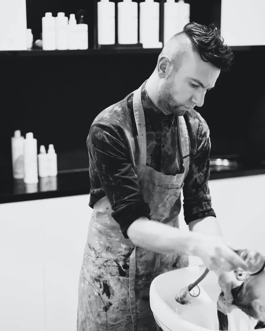 Ryan washing a client's hair at the basin
