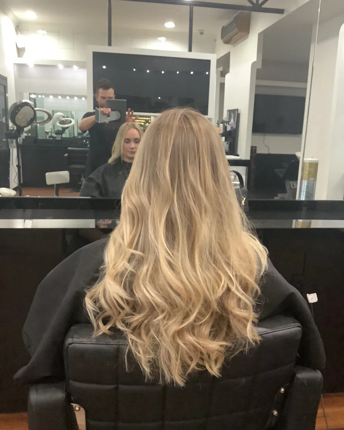 A finished blonde colour and blow-dry, photographed from behind in the salon chair